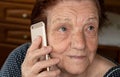 Elderly senior woman holding gold coloured phone next to her ear, closeup detail. Royalty Free Stock Photo