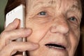 Elderly senior woman holding gold coloured phone next to her ear, talking - closeup detail Royalty Free Stock Photo