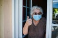 Elderly senior woman opening a window of her house Royalty Free Stock Photo