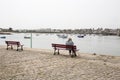 An elderly senior woman sits on a bench as she watches the view at the seafront and the boat. Loneliness of senior people concept