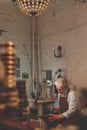 An elderly shoemaker in uniform indoors