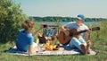 An elderly slender couple arranges a romantic picnic on the beach on a sunny summer day: a man smiles and plays Royalty Free Stock Photo