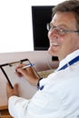 Elderly smiling doctor sits at his desk Royalty Free Stock Photo