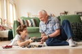 Elderly smiling grandfather giving little funny grandson present on holiday on warm floor among toys Royalty Free Stock Photo