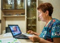 Elderly a smiling woman uses the online system of the bank to pay the bills