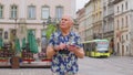 Elderly stylish tourist man looking for way find route using smartphone in old town Lviv, Ukraine