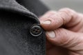 Elderly tailor expertly sewing a button onto a coat in a cozy workshop atmosphere Royalty Free Stock Photo