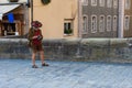 An elderly tourist on a cobblestone pavement with a camera and in the national Bavarian clothes
