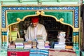An elderly Tunisian man inside his bookshop selling books and souvenirs to tourists near Ez-Zitouna mosque.