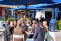 Elderly Tunisian men sit under umbrellas in the cafe and enjoy the morning with tea or coffee