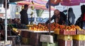 Elderly Tunisian woman wearing a headscarf checks the oranges at a fruit stall
