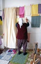 A elderly Turkish lady hanging up her handmade items