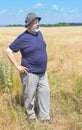 Elderly Ukrainian senior wearing hat while standing in wheat field