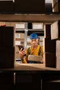 Elderly warehouse worker inventory manager using digital tablet works standing near shelves full of parcels ready to be Royalty Free Stock Photo