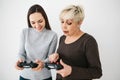 The elderly woman asks the young girl how to use the joystick for video games and shows her finger on the buttons Royalty Free Stock Photo