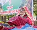 An elderly woman in Bashkir clothes embroiders a crochet pattern. Traditional national holiday Sabantuy in the city park