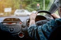 Elderly woman behind the steering wheel of a car. Cheerful senior woman driving a car. Old lady in glasses drive the car