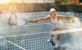 Elderly woman bouncing ball in tennis game on court with racket Royalty Free Stock Photo