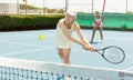 Elderly woman bouncing ball in tennis game on court with racket Royalty Free Stock Photo