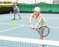 Elderly woman bouncing ball in tennis game on court with racket Royalty Free Stock Photo