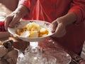 An elderly woman in brightly colored clothes sets the table, holds, and offers homemade diet potato soup as she treats guests.