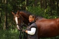 Elderly woman and brown horse portrait in the forest Royalty Free Stock Photo