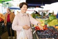 Elderly woman buys plums at an open-air market