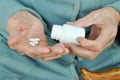 An elderly woman with a cane holding a pill and a container on the street. Health.Mockup. Close up. Royalty Free Stock Photo