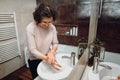 Elderly woman washing hands with soap and sanitiser in home bathroom. top view, details of good hygiene