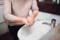 Elderly woman carefully washing hands with soap and sanitiser in home bathroom. top view, details of hygiene