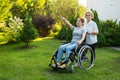 An elderly woman is carrying an adult daughter sitting in a wheelchair. Caucasian woman pointing her finger admiringly Royalty Free Stock Photo