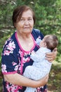 Elderly woman carrying a baby in arms, great grandmother portrait with her great grandchild Royalty Free Stock Photo