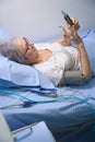 Elderly woman is chatting on mobile phone from hospital room