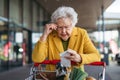 Elderly woman checking her receipt after purchase, looking at amount of money spent, ensuring all charges are correct. Royalty Free Stock Photo
