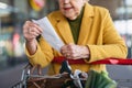 Elderly woman checking her receipt after purchase, looking at amount of money spent, ensuring all charges are correct. Royalty Free Stock Photo