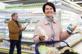 Elderly woman chooses milk in supermarket Royalty Free Stock Photo