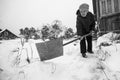 An elderly woman cleans the snow near her house in the russian village. Black and white photo. Royalty Free Stock Photo