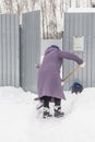 An elderly woman cleans the snow near her house in the village Royalty Free Stock Photo