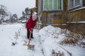 An elderly woman cleans the snow near his home. Royalty Free Stock Photo