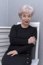 An elderly woman clutches a metal brass knuckles while sitting on a chair in the room. Concept, women`s self-defense, traumatic ob