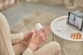 An elderly woman communicates remotely via a tablet with her doctor and takes medications according to his recommendations. Royalty Free Stock Photo