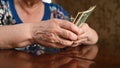 An elderly woman counts dollars. Last money for life, low incomes, poverty, 1 dollar bills. Royalty Free Stock Photo