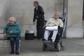 An elderly woman at Covent Garden. An elderly man in a wheelchair watching a show at Covent Garden