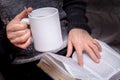 An elderly woman with a cup of tea in hand reads a book. Reading the Bible_ Royalty Free Stock Photo