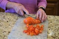 Elderly woman cuts tomatoes on counter Royalty Free Stock Photo