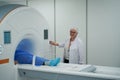Elderly woman diagnostician performs an MRI procedure