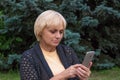 Elderly woman dials or texts on mobile phone