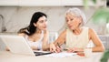 Elderly woman discussing deal with saleswoman in kitchen