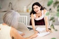 Elderly woman discussing deal with saleswoman in kitchen