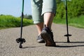 Elderly woman does Nordic Walking on an asphalted field road. Female legs with Nordic Walking poles on a cartway Royalty Free Stock Photo